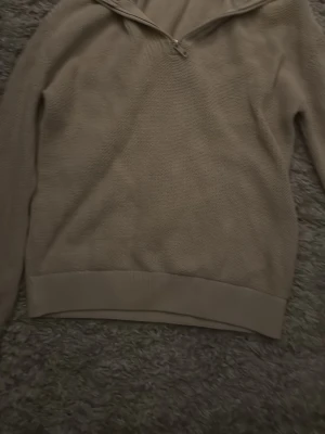 Beige stickad tröja med half zip Kappahl - Beige stickad tröja från Kappahl med half zip-dragkedja vid halsen. Tröjan har lång ärm och ribbade muddar vid ärmslut och nederkant. Perfekt för lager på lager och enkel att matcha med olika stilar.stor i storleken så typ en 150