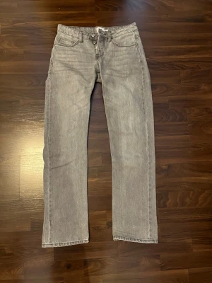Grå raka jeans från 157 Icon - Snygga lågmidjade grå jeans från 157 Icon med rak passform. Jeansen har en ljus tvätt och är tillverkade i ett mjukt denimtyg som ger en avslappnad vibe. Perfekta till en streetwear-look eller för att lyfta din vardagsstil.