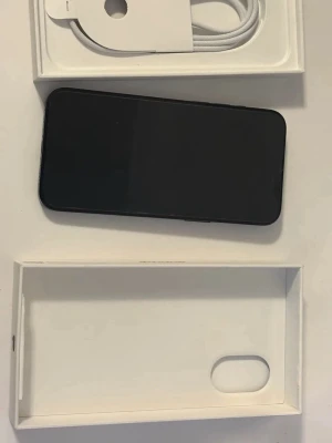  iPhone 15 Pro 256 gb med box - Säljer en snygg svart iPhone 15 Pro med stilren design och platt kant. Telefonen har tre kameror på baksidan och levereras i originalkartong med laddkabel. Baksidan är i glas och ramen i metall, vilket ger en premiumkänsla. Perfekt för dig som vill ha en modern och kraftfull mobil.