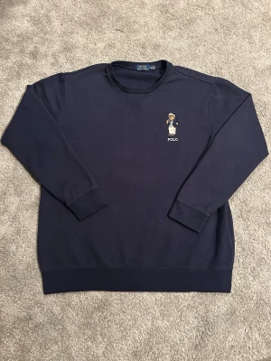 Marinblå Ralph lauren beer tröja - Riktigt snygg Polo Ralph lauren tröja med Ralph slutens teddy Björn på bröstet. Varsamt använd och har inga defekter eller fläckar Skriv vid mer frågor Pris ej hugget i sten