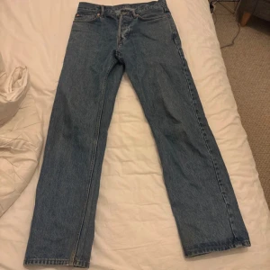 Blå raka jeans med hög midja - Klassiska blå jeans från Weekday med rak passform. Jeansen har stängs med knappar. Tillverkade i ett slitstarkt denimtyg som ger en tidlös look. Perfekta för en avslappnad och trendig stil.