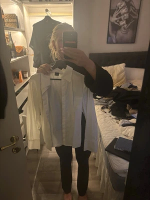 Vit klassisk skjorta med knappar - Säljer en stilren vit skjorta med klassisk krage och långa ärmar. Skjortan har knappar framtill och breda manschetter för en clean look. Perfekt att styla till jeans eller kostymbyxor.