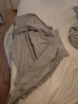 Randig skjorta från Sandö, strl 46 - Säljer en stilren skjorta från Sandö i storlek 46. Skjortan är ljusgrå med tunna vita ränder, har lång ärm och klassisk krage. Perfekt för dig som gillar en clean och enkel look. Knappar framtill och mjukt bomullsmaterial. Pris kan diskuteras!