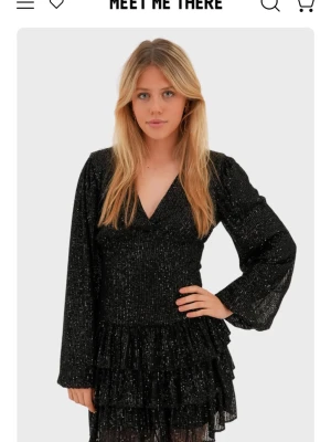 Svart glittrig omlottklänning Meet Me There - Säljer min helt oanvända klänning jag beställde till nyår som ej passade, och var försent att skicka tillbaka, ny pris 650kr, svart glittrig volangklänning med v ringning, pris kan diskuteras 