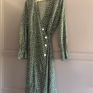 Klänning - En grön/vit omlottklänning med lång ärm och konstknappar. Endast provad. 