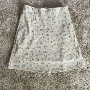 Blommig kjol från Nelly  - Säljer denna söta kjolen från Nelly. Säljer pågrund ut av att den är lite stor i midjan för mig. Kjolen slutar presic ovanför knäna och har resår i midjan. Den har även ett innertyg så det lyser inte igenom. Den är endast testad, så i väldigt bra skick. Frakt tillkommer! 