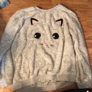 Långärmad tröja med kattansikte  - Köpte tröjan för flera år sen på Cubus  Använt den säkert några gånger, sen bara legat och samlat damm.   jag står ej för postens slarv & den ligger hos mamma och kommer ta 1-2 dagar innan den blir skickad efter betalning 