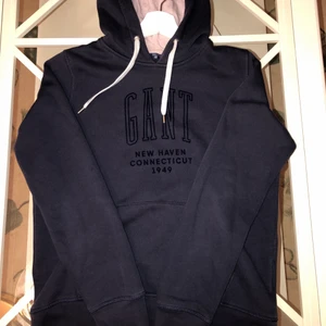 GANT HOODIE - En mysig marinblå Gant hoodie som köptes för 1199:-  på NK. Använd enbart ett fåtal gånger. Insidan av hoodien är i mjukt varmt material och texten är i velvet textil. Inuti luvan är det en rosa/lila. Hoodien är bland de sista exemplaren då det var en limited edition och säljs inte längre. Vid texten är det två små oljefläckar vid texten (se tredje bild) men som är knappt märkbar för blotta ögat. Startpris 190:-, köparen står för frakten, kan mötas upp i Gbg💗. (Kan skicka fler bilder vid efter