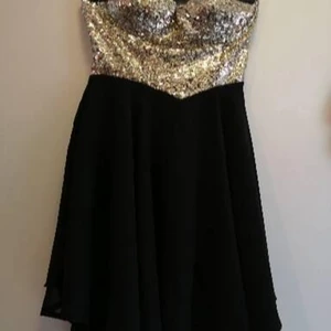 Guldglittrig paljettklänning  - Axelbandslös klänning i svart med guldpaljetter. Stl S i nyskick 