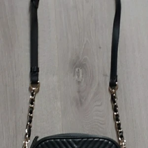 Väska  - En svart hand väska långt band 3 fickor dragkedja.