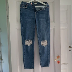 Gina mom jeans - Gina mom jeans i en mörkare blå, slitningar på knäna. Aldrig använda (pga försmå) men avtagen prislapp. Frakt tillkommer men priset är diskuterbart!