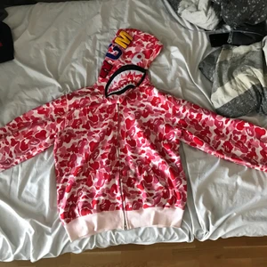 Pink Bape shark fullzip - Asclean pinkcamo bape shark fullzip, bootleg men fet som fan ändå. Dragkedjan krånglar lite ibland men annars är d asbra skick💪 d står XXL på sizetagen men den sitter som clean baggy L typ. Skriv för fler bilder eller frågor💯