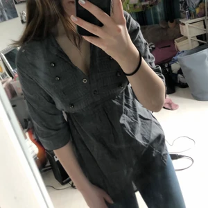 Grå blus  - Grå blus från kina, Står XL på den men jag upplever den XS om inte lite mindre, Själv har jag XS i flesta kläder men kunde inte stäcka knapparna på armarna, Var lite trångt för brösten med. (Cupa C)