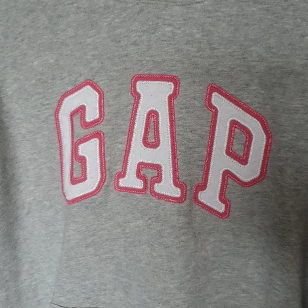 GAP hoodie, Grå med rosa och vita bokstäver. Står strl M men sitter som en S. Välanvänd men bra skick. Hoodies.