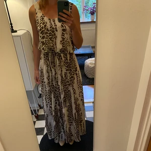 Fladdrig leopardmönstrad långklänning - Den här klänningen fladdrar härligt i vinden och har en skön innerkjol i silkesliknande material. Från Gina Tricot i strl 38. Använd med eller utan det medföljande skärpet. Överdelen är superloose och baksidan har en djupare u-ringning är framsidan. Använd i sommar. 