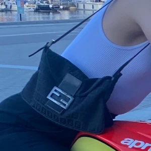 Äkta Fendi väska - Äkta väska från Fendi! Väl använd och lite sliten här och där. Tyget inne i väskan är slitet och metallmärket har revor i sig. Men fortfarande väldigt fin❤️ säljer pga för lite användning på senaste. Köp direkt för 2500kr