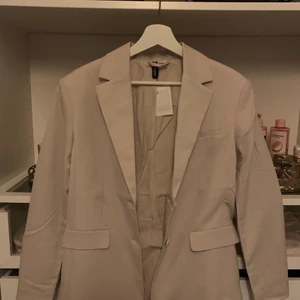 KRÄM FÄRGAD KAVAJ - Elegant oanvänd kavaj! Prislappen står till och med kvar; köptes för 500kr! Passar snyggt med jeans eller kostymbyxor. Går även för er mer storlek XS-S. Budgivningen startar från 100kr. Frakt tillkommer!