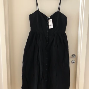 Långklänning HM - Långklänning med knappt från bysten ner till follen av klänningen. Den är i nyskick med lapp kvar och ej använd. 
