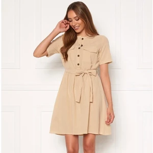 Klänning från Pieces i strl L - En biege klänning från Pieces med knappar av trä fram. Den har två bröstfickor samt ett avtagbart band i midjan🤎 aldrig använd bara prövad, säljer eftersom den inte är min stil och inte kommer till användning! Köparen står för frakten🤍