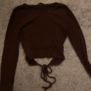 Asfin brun långärmad tröja - En skittsnygg långärmad brun tröja med ett knyte baktill som en fin detalj! Tröjan är ribbad! 