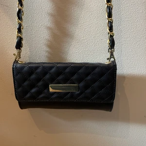 Liten svart väska med guld - Liten väska, har fack för kort eller mynt. Mobil skulle få plats. Bra skick. Frakt tillkommer 66kr. 