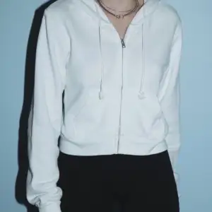 Kort, croppad hoodie från Brandy Melville, använd ett fåtal gånger, i bra skick utan några fläckar eller märken. Köpt i San Diego. One size, frakt tillkommer 