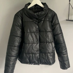 Pufferjacket i skinnimitation - Svart pufferjacket (vadderad jacka) i skinnimitation från Only. Två fickor på vardera sida och knappar för att stänga den. Så snygg! Storlek XL. 