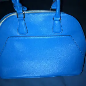 En vacker blå handväska i leder. Aldrig använda då jag föredrar svarta eller bruna handväskor. Rymmer en iPad och har fungerande dragkedja med innerfack. Köpare står för frakt 