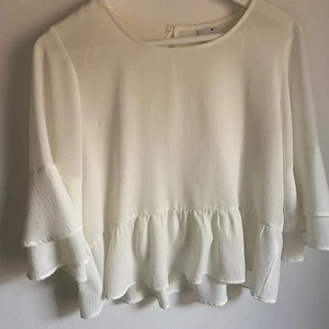 Volangblus Gina Tricot - Vit blus med volanger från Gina Tricot. Använd fåtal gånger. Storlek XS. Köparen står för frakten. Betalning sker via SWISCH. 