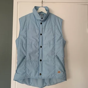 Blå dunväst - Säljer denna ljusblåa vintage dunvästen i storlek M. Skulle säga att den passar allt från XS-M. Pris: 200kr + frakt