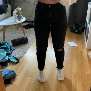 Svarta momjeans - Svarta mom jeans från Gina tricot. Nyskick. Hål i höger knä och slitna längst ner 💘 tveka inte på att ställa frågor om det är något du undrar!