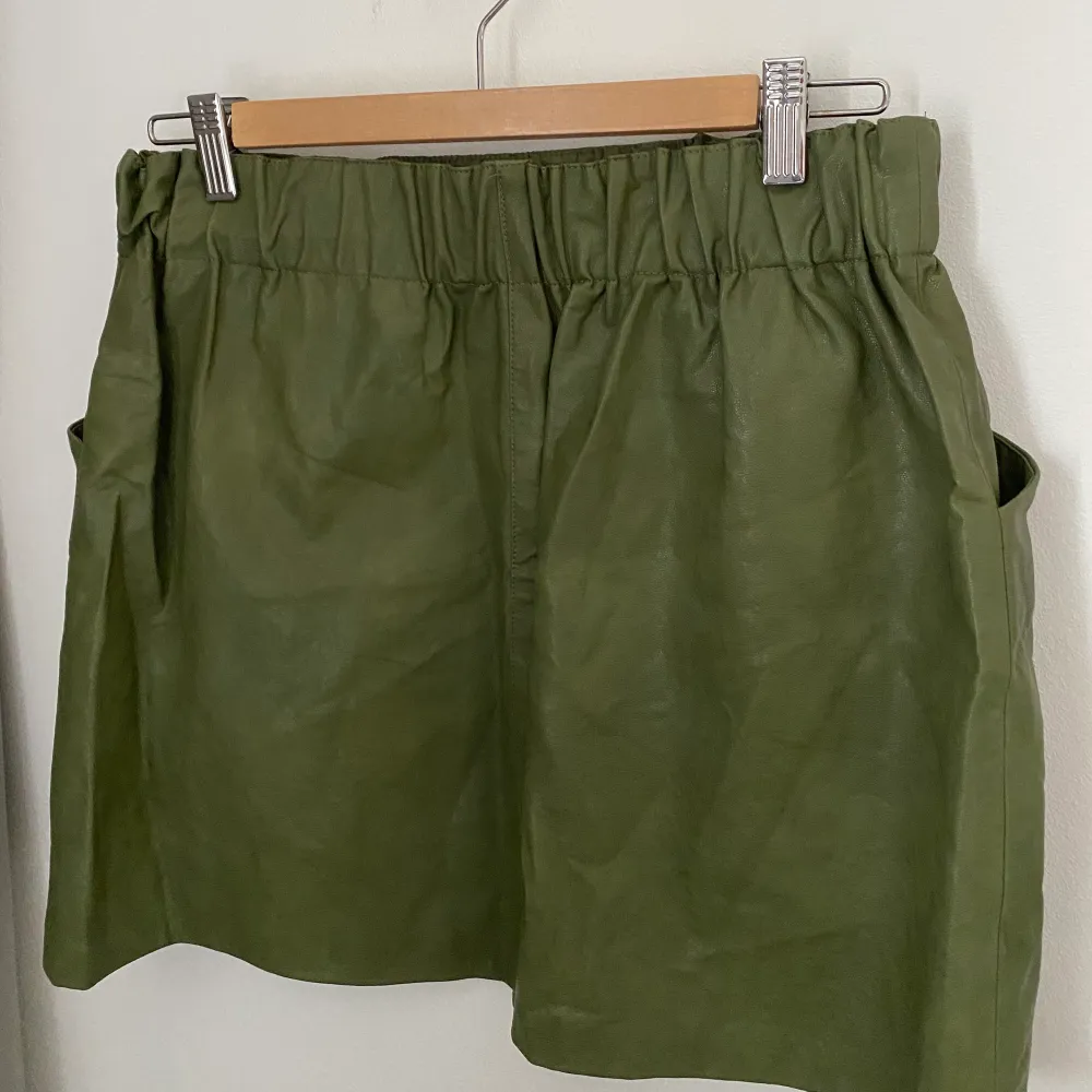 En jättefin grön kjol i skinnimitation från Zara. Kjolen är aldrig använd och är i storlek L och har två fickor framtill. Köparen står för frakten. . Kjolar.
