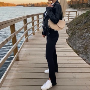 Svarta byxor med slits  - Svarta stretchiga byxor med söm över benen och slits nertill