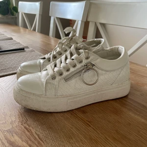 Vita sneakers med silver detaljer - Säljer nu mina vita sneakers med silver detaljer eftersom det inte kommer till användning längre. Har använt dom några gånger. Skulle säga att det är storlek 37 men funkar till dom som vanligtvis har 38 också. 