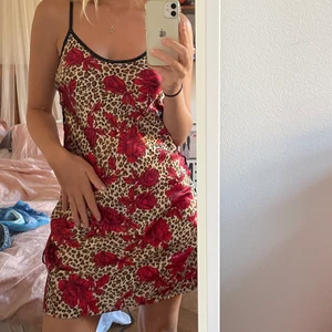 Mönstrad nattlinne/klänning - Skitcoolt nattlinne i siden med leopardmönster och röda rosor på. Den har snörning i sidorna så går att ändra hur den sitter, har även justerbara axelband. Endast använd några gånger. Står storlek 38/40 men passar fler beroende på hur man vill att den ska sitta. 