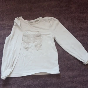 Vit långärmad med glittrig rosett - Använd ett par gånger men den är inte i såpass dåligt skick men är lite skrynklig samt ingen fläck som jag kunde se.