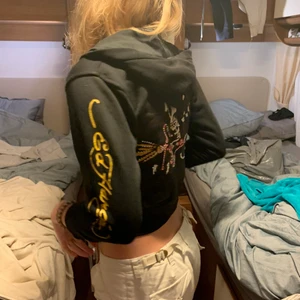 Ed Hardy kofta - Skitcool ed Hardy kofta i barnstorlek (128) men funkar som en cropad luvtröja! Bra skick förutom några hål längst ner på ena armen (kolla tredje bilden)