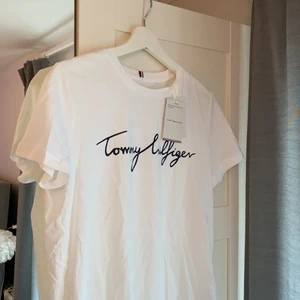 Tommy hilfiger T-shirt  - Vit Tommy hilfiger T-shirt med marinblå text. Aldrig använd!!!! Lappen är kvar💜💜💜💜