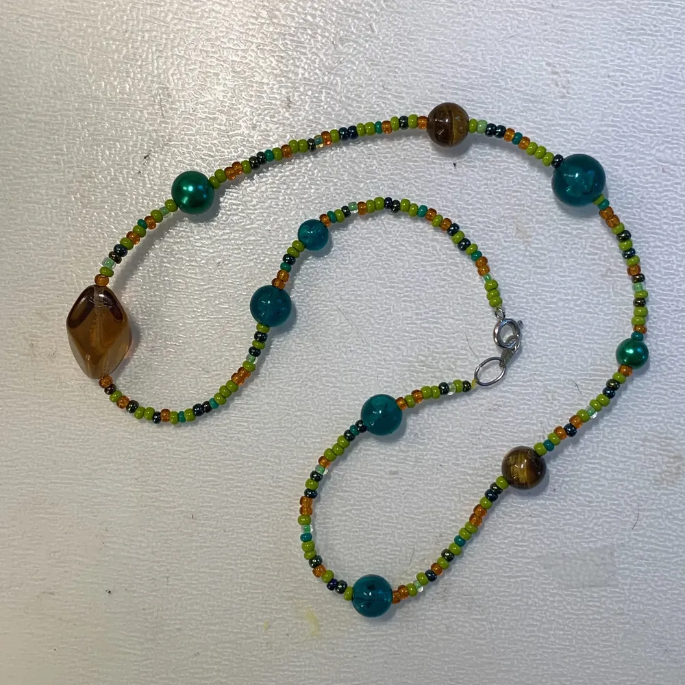 Pärlhalsband med olika bruna och gröna pärlor i olika storlekar och pärlor av kristallen tigeröga🌲🪵🌱🐅. Accessoarer.