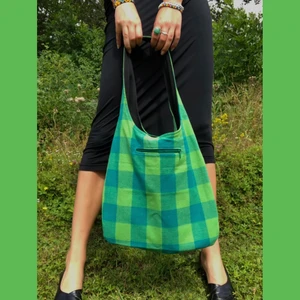 Tygväska/tygpåse i grönt retromönster - En väska i modellen ”Frida” med både två större fickor och en ficka med dragkedja. Väskan går alltså att vända ut och in, så det är 2in1 kan man säga. Tyget är från en äldre retro duk, extremt härliga färger. Den är egensydd och egen designad. 