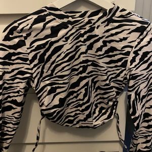 zebra trop med öppen rygg - fin topp i skönt material som säljs i nyskick då den endast är testad :) toppen har lite som en polo tröja och är öppen i ryggen samt att man kan knyta den :) 