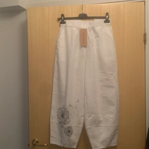 Vita byxor  - Säljer ett par vita byxor, tyget är svalt och lite stelt. Det är inte töjbart tyg. Strl 40/M. Lapp kvar så helt oanvända. (Dåligkamera, drf är det lite prickar o suddigt) 