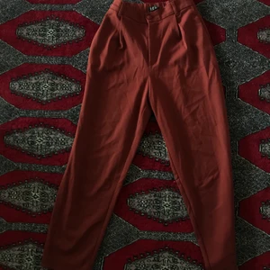 Raka röda kostymbyxor - Högmidjade röda kostymbyxor. Dragkedja och knapp. Sparsamt använda. Skriv för fler bilder/mått! Allt så bort på min sida pga flytt! Priser går att diskutera! :)