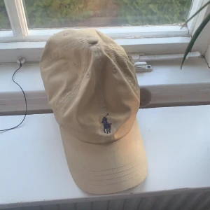Keps - En Polo Ralph Lauren Keps med färgen Beige. I användt  skick men säljs för bra pris. Orginalpris är 400kr