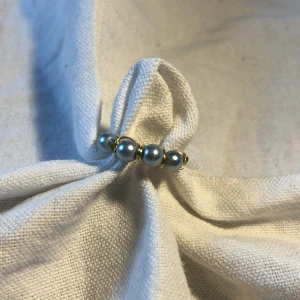 Hemmagjord ring  - En hemmagjord ring med 4 blå/silvriga pärlor på. Metalltråden är i färgen guld. Passar bra till mycket. 70 kr med frakt 🚚 