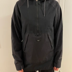 Svart skidjacka - Skidjacka från Armada, gott skick, har ett slags ”trä” mönster på fickan och armarna som syns i vissa ljus. Anorak modell som går att dra upp helt med dragkedjor på sidorna och halvvägs ner på bröstet. Ganska tunn, mer som en skaljacka!