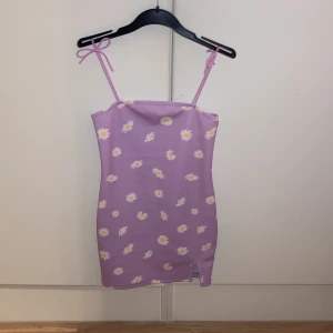 Lila blommig klänning  - Jätte skönt material, bra längt, inte för kort, axel banden är lite stora så dom kan pka ned💗 storleken är 134 men passar också till 140(jag har 140-150)