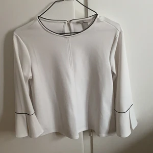 Vit blus strl. XS/S - Vit fin blus som inte är genomskinlig. Köpt på H&M och använd ett fåtal gånger. Inga fläckar. Knäpps vid nacken på baksidan med en enkel knapp. Storleken är XS, men den passar även S. Blusen är rak i modellen.