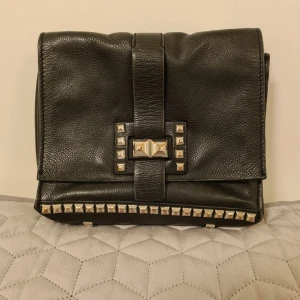 Skinnväska med nitar  - Svart skinnväska med nitar. Några nitar är lite slitna men i övrigt är den i bra skick. 