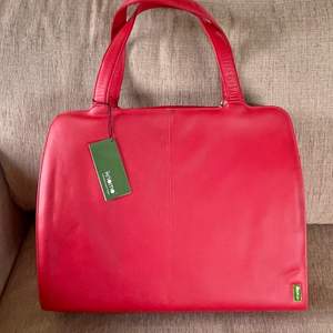 Praktiskt väska i härlig röd färg i äkta läder av märket Knomo - För din dagliga användning, oavsett om det är en dag på jobbet eller din lediga dag, med tillhörande datorväska som även kan användas separat. Helt NY, aldrig använd.   Mått 41x32 Djup 13 cm 
